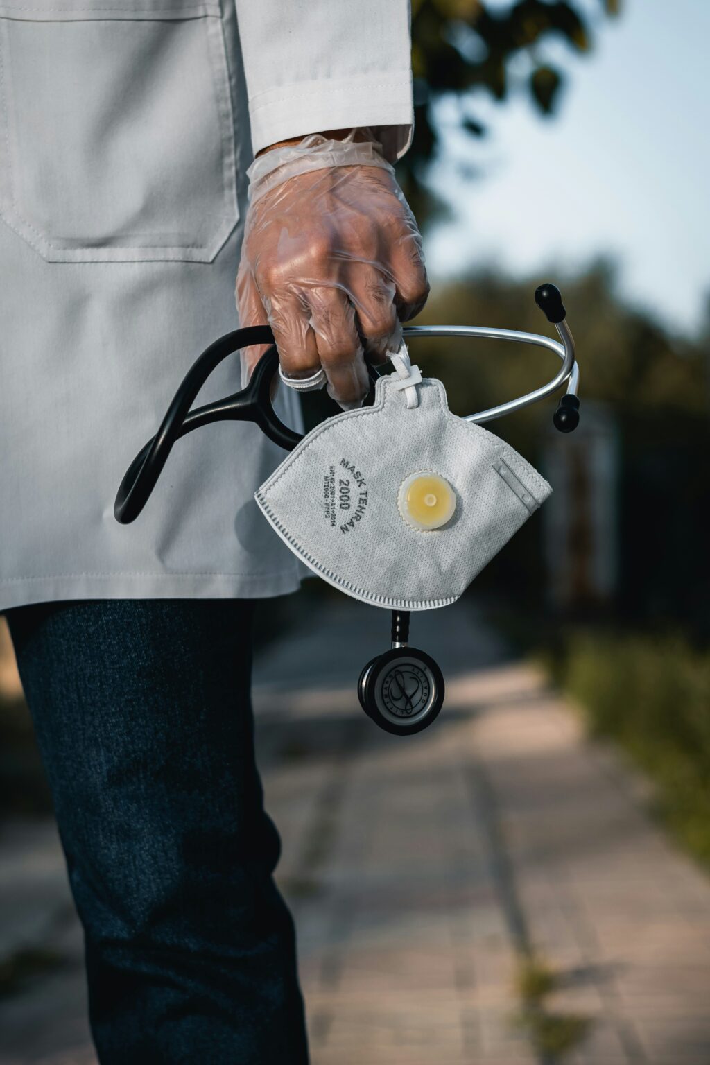 A doctor wearing gloves while holding a mask and a stethoscope